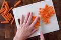 WomanÃ¢â¬â¢s hands chopping baby carrots, white cutting board on wood butcher block